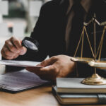 Private InvestigationOf Lawyer Examining Paper Through Magnifying Glass By Gavel On Desk